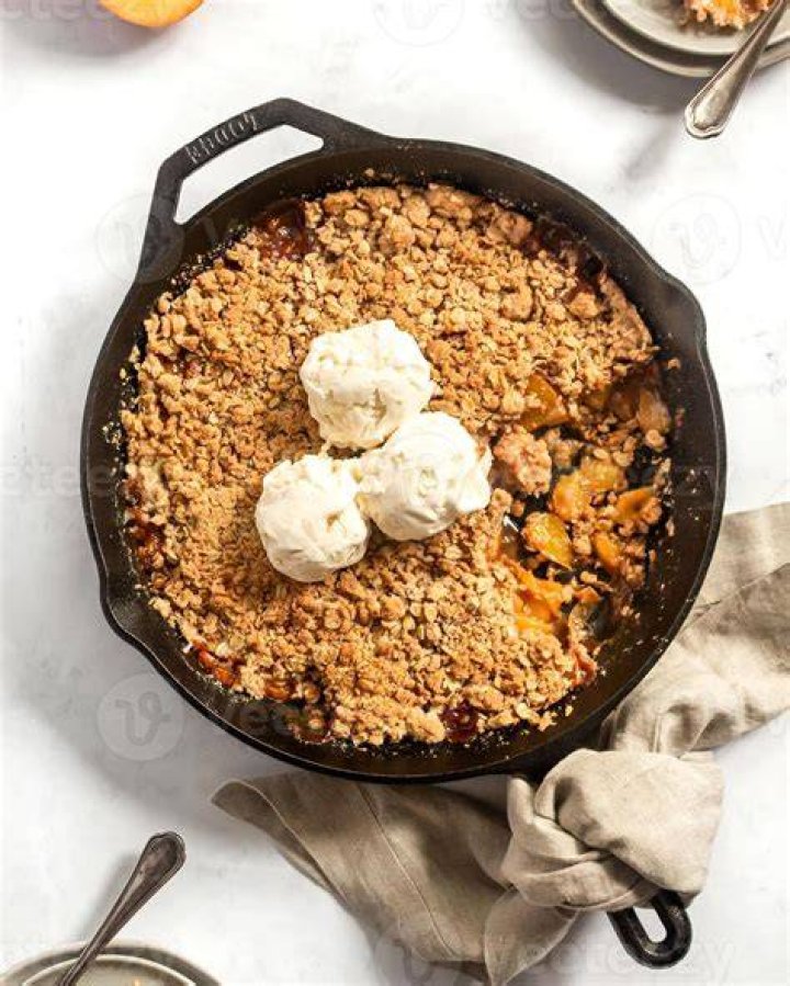 A cast iron skillet filled with golden brown smashed potatoes drizzled with honey garlic sauce