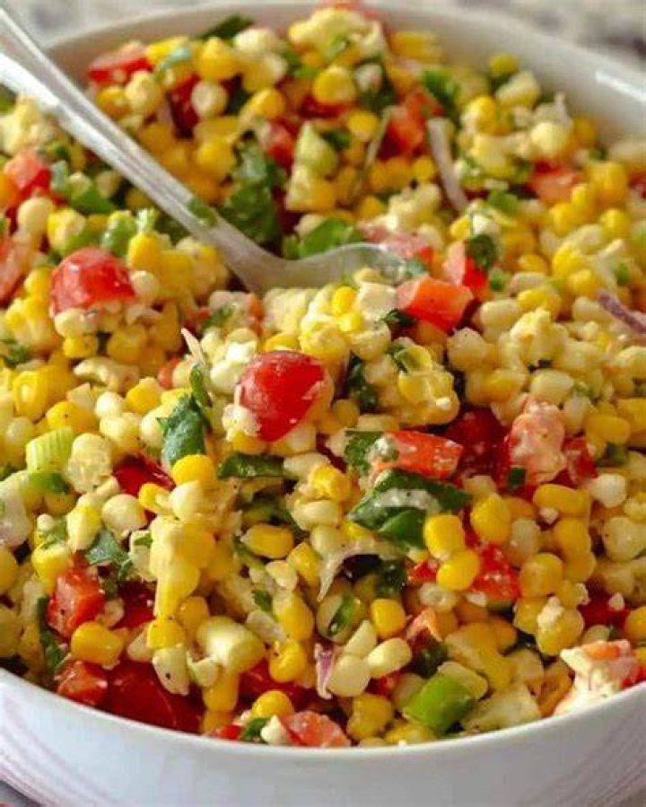 Fresh corn salad with lime and cilantro on white plate