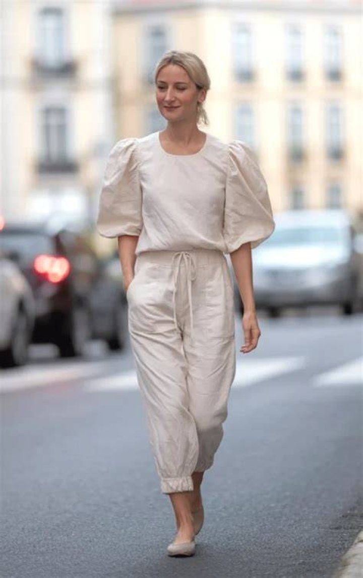 Woman in white puff sleeve blouse with tailored straight leg trousers and minimalist jewelry