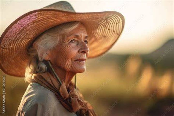 Woman wearing a stylish sun hat while working in a beautiful garden
