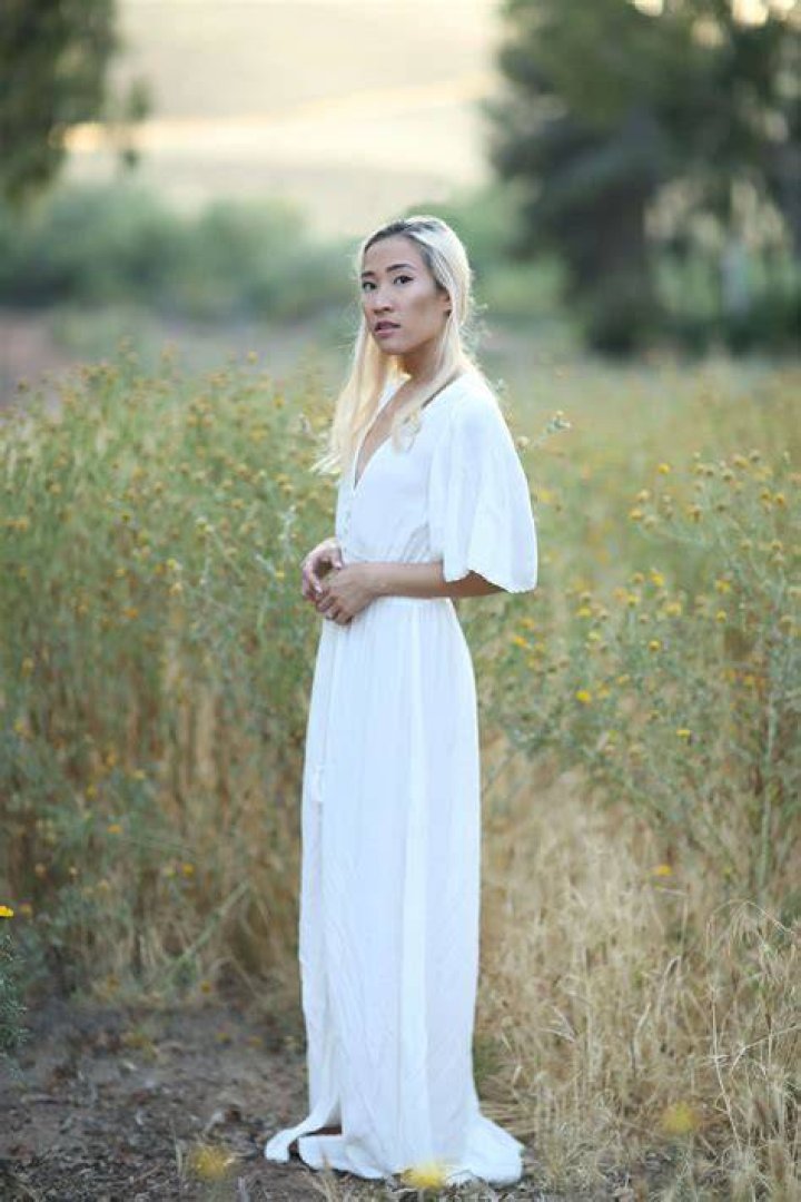 Woman wearing a white summer dress and minimalist hairstyle walking outside